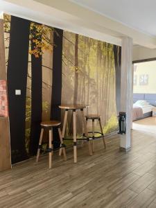 a room with a table and two stools in a forest mural at Apartamenty Buczyna w Sierakowie in Sieraków