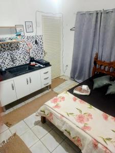 a small bedroom with a bed and a kitchen at Harmonia Studio Mobiliado in Campo Grande