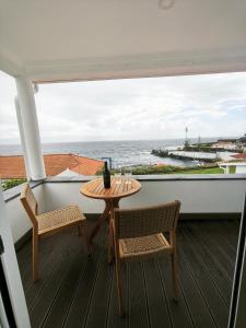 a table and chairs on a balcony with a view of the ocean at Casa d'Avó Guesthouse and Apartment in Urzelina