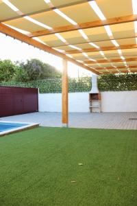 an outdoor patio with a wooden pergola and green grass at Páteo da Chica in Cano