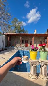a person is pointing at three vases with flowers in front of a house at Pergamon Yunt Evleri in Bergama