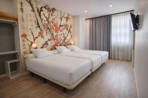 two beds in a hotel room with a painting on the wall at Eibarooms in Éibar
