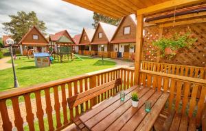 a wooden deck with a bench and a playground at Domki SUNSET Bałtycka in Dąbki