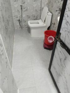 a bathroom with a toilet and a red trash can at Jay shree Kedar room in Ujjain
