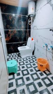 a bathroom with a white toilet and a black and white tiled floor at Jay shree Kedar room in Ujjain