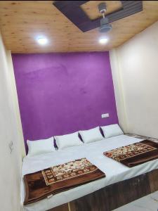 a bed in a room with a purple wall at Jay shree Kedar room in Ujjain