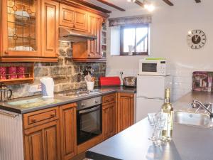 a kitchen with wooden cabinets and a white refrigerator at The Granary in Bucknell +7 photos