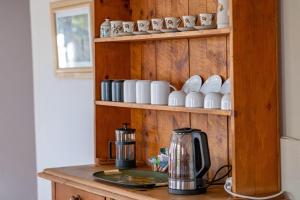 a counter with a coffee maker and cups on a shelf at Olive's Cottage in Molteno