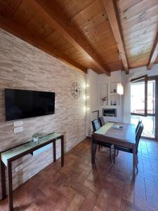 a dining room with a table and a tv on a brick wall at Copelia - Pool and Elegance in Paratico