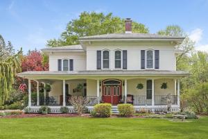 a white house with a red door and a yard at Monroe Manor Inn in South Haven