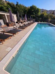 a swimming pool with lounge chairs and umbrellas at DESIGN hotel VERBENICUM in Vrbnik