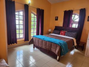 a bedroom with a bed and two windows at Hideout by Cloudwalks in Kodaikānāl