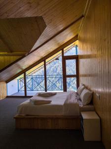 a bedroom with a bed in a room with windows at The Blue Mont Sojha Jibhi in Shoja