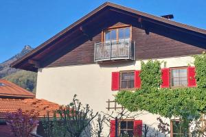 a building with red shutters and a balcony on it at Ferienwohnung Scheibenwand-Loft in Aschau im Chiemgau