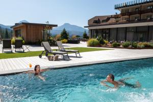 a man and a woman swimming in a swimming pool at Hotel Cristal in Obereggen