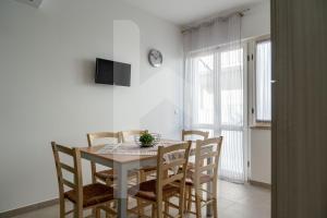 a dining room table with chairs and a clock on the wall at Homiday - Appartamento Via Roma, 32 in Pineto