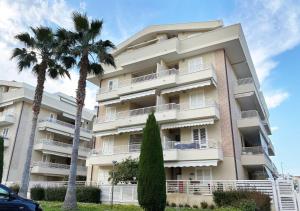 a tall building with palm trees in front of it at Holihome Hill View in Tortoreto Lido