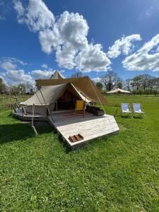 a tent in a field with two chairs and a table at Belltent 't Bievink - buitengewoon overnachten in Westendorp