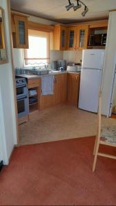 a kitchen with wooden cabinets and a white refrigerator at The discovery whitehouse towyn in Kinmel Bay
