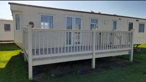 a mobile home with a porch and a fence at The discovery whitehouse towyn in Kinmel Bay