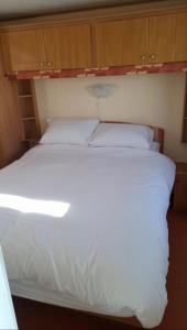 a large white bed in a room with wooden cabinets at The discovery whitehouse towyn in Kinmel Bay