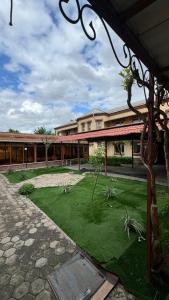 a building with a courtyard with a grass yard at Aruzhan Hostel in Shymkent