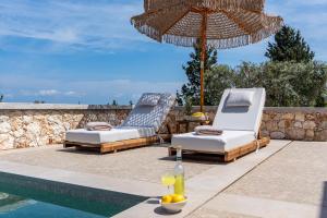 two lounge chairs and an umbrella next to a swimming pool at Veragi Boutique Villas in Lefkada