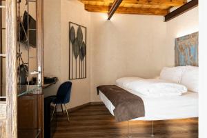 a bedroom with a white bed and a blue chair at Domus Mea Suites in Costermano