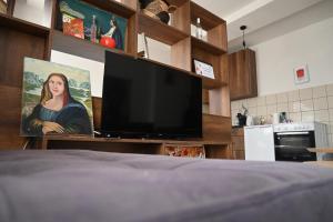 a bedroom with a television and a painting of a woman at Mimosa Apartments - City Center Square in Prishtinë +11 photos