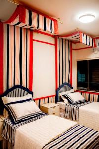 two beds in a room with striped walls at Chick Nina Loft in Barra do Garças