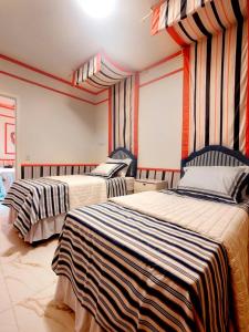 two beds in a room with striped curtains at Chick Nina Loft in Barra do Garças