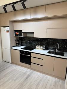 a kitchen with white cabinets and black appliances at ЖК Сити Парк in Osh +3 photos