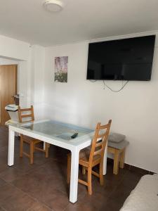 a white table with chairs and a television on a wall at Travellers' Haven Hostel in Bled