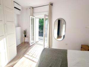 a white bedroom with a bed and a mirror at Luz de Belén in Jaén