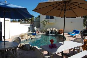 a patio with a pool with tables and an umbrella at Pescadero Palace in El Pescadero