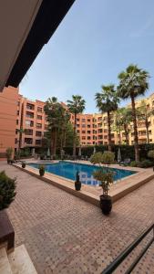 a large building with a swimming pool and palm trees at Appartement 6 personnes piscine hivernage Marrakech in Marrakesh