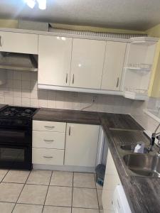 a kitchen with white cabinets and a sink at 8 mins Drive from Heathrow - Double bedroom in shared accommodation - Cavalier Gardens in Hillingdon