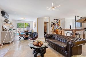 a living room with a leather couch and a table at Villa Bleu Azur - piscine, plages in Angles
