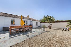 a patio with two benches and a yellow umbrella at Villa Bleu Azur - piscine, plages in Angles