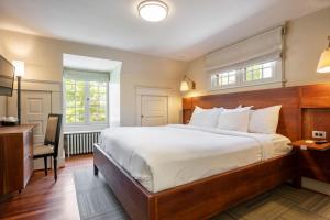 a bedroom with a large white bed and a desk at Oakhurst Inn at the University in Charlottesville