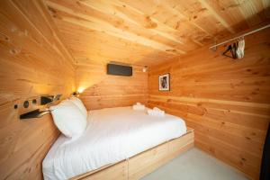 a small bedroom in a wooden cabin with a bed at Cabane Cala - Coeur d'Arcachon in Arcachon