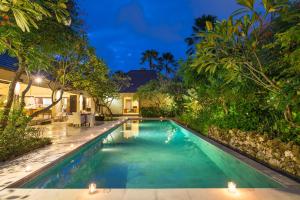 a swimming pool in the backyard of a villa at night at Villa Roku by Nagisa Bali in Seminyak