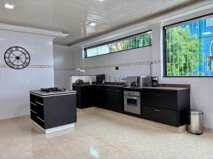 a kitchen with black cabinets and a clock on the wall at Julietta House Hotel in Manaus