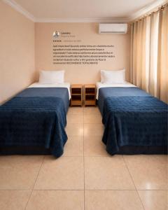 a room with two beds and a sign on the wall at Apê 202 - Central, Garagem e Ar Cond - 2Q e 2B in Governador Valadares