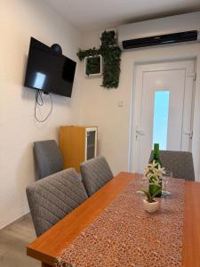 a dining room table with chairs and a television on the wall at Apartman Kata in Šmrika
