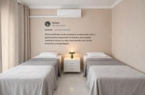 two beds in a room with a sign on the wall at Apê 401 - Central, Garagem e Ar-Condicionado - 2Q in Governador Valadares