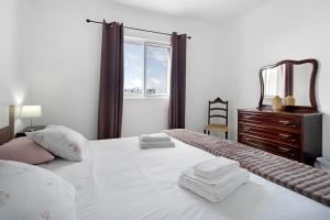 a bedroom with a white bed with a dresser and a window at Carmen's Place in Ponta Garça