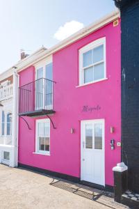 a pink building with a balcony on the side at Magenta - A stunning Seafront house with lovely and uninterrupted Beach Views - Aldeburgh Coastal Cottages in Aldeburgh