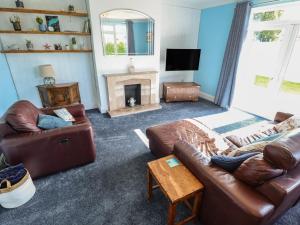 a living room with a leather couch and a fireplace at Sorrento in Mablethorpe