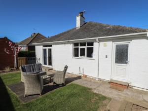 a white house with two chairs in a yard at Sorrento in Mablethorpe